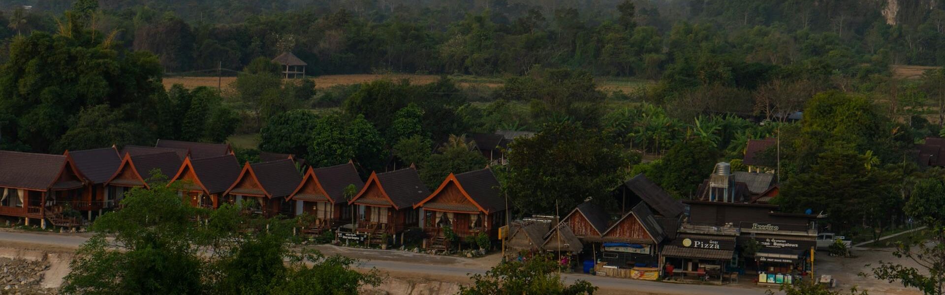 Misty Vang Vieng karst hills at dawn for a Vang Vieng Travel banner by Legend Travel Group.